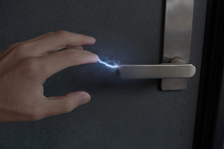 Hand getting static shock from metal door handle.